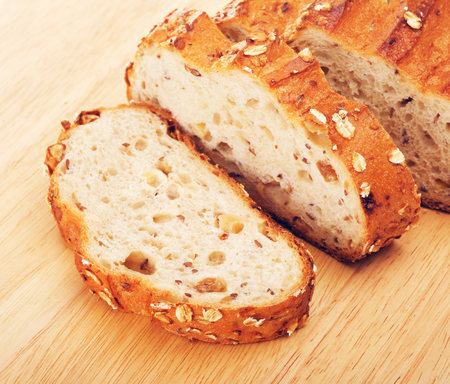 sliced wholegrain bread with oats and nuts, on cutting boardの写真素材