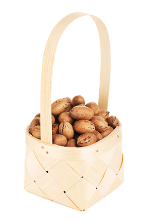 pecan nuts in wooden basket, isolated on white backgroundの写真素材