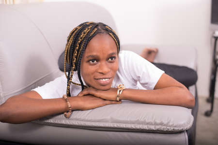 Happy young African American woman lying on the sofaの写真素材