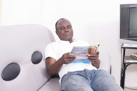 Man with magazine on sofaの写真素材