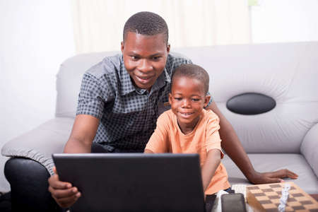 Happy father teaching his son how to work with a computer