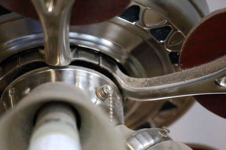 Close up view of a ceiling fan with brown wooden blades and four light bulbsの写真素材
