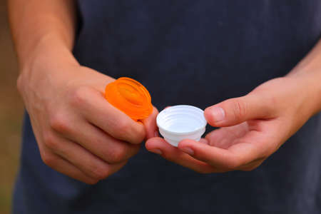 Close up view of someone opening up an orange prescription bottle with a white top