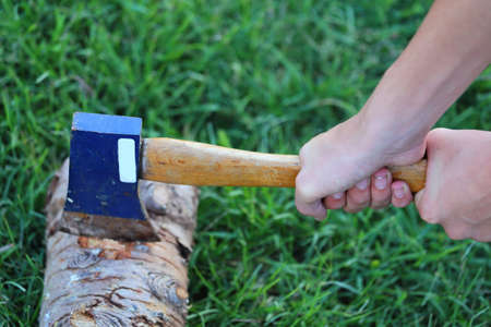 Close up view of someone using a hatchet with both hands to cut through a log