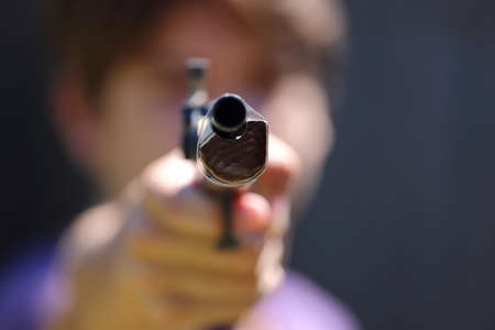 A close up view of someone pointing a gun at the camera  の写真素材