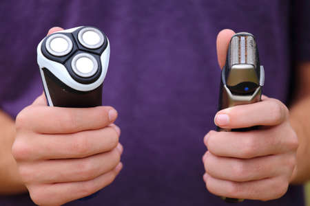 Someone holding up two different types of razors の写真素材