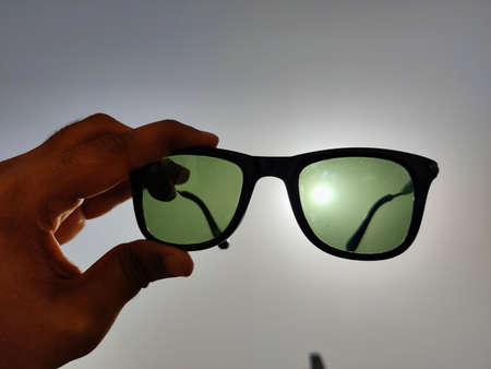 Picture of a black sunglass shot against bright sun and blue depicting use of sunglasses in heavy...