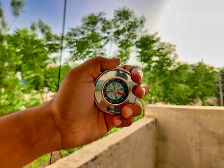 Picture of a compass made of metal shot against blur background in summers during daylight used for directions by travelersの写真素材