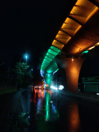 Image of like streaks of vehicles and a flyover illuminated in saffron, white and green