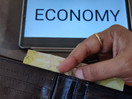 Picture of a person taking out money from his wallet. ECONOMY with an upward pointing arrow is written in background. Picture is depicting economic growth.の写真素材