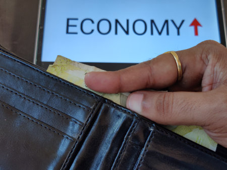 Picture of a person taking out money from his wallet. ECONOMY is written in background. Picture is depicting economic growth.の写真素材