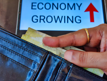 Picture of a person taking out money from his wallet. ECONOMY GROWING with an upward pointing arrow is written in background. Picture is depicting economic growth.の写真素材
