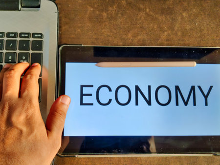 Picture of a person using laptop. ECONOMY with a downward pointing arrow is written in background. Picture is depicting economic fall.の写真素材