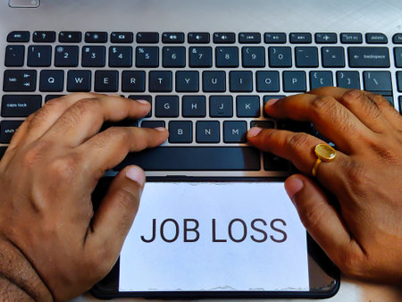 Picture of a person working on a laptop with  JOB LOSS written on a screenの写真素材
