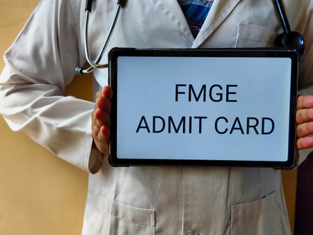 Picture of a doctor wearing a white apron with a stethoscope is holding a placard with FMGE ADMIT CARD written on it. FMGE is a medical exam in INDIA for foreign medical graduatesの写真素材