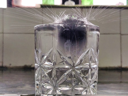 Water splashing into a glass with ice cubes on the table.の写真素材