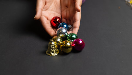 Christmas Balls, Crop view of young girl hand holding christmas balls isolated in black background for christmas decoration.の写真素材