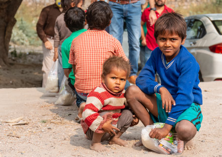 NOIDA, UTTAR PRADESH, INDIA - NOV 2020 : Portrait of poor kids or students from slum or village area standing in school ground to collect food distributed by volunteers during corona pandemic.のeditorial素材