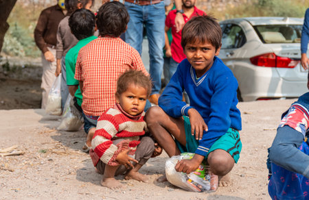 NOIDA, UTTAR PRADESH, INDIA - NOV 2020 : Portrait of poor kids or students from slum or village area standing in school ground to collect food distributed by volunteers during corona pandemic.のeditorial素材