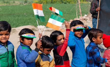 NOIDA, UTTAR PRADESH, INDIA - JANUARY 2020 : Young Indian students from Slum or Village area celebrating Indian Republic Day function at school with Indian National flag in hand.のeditorial素材