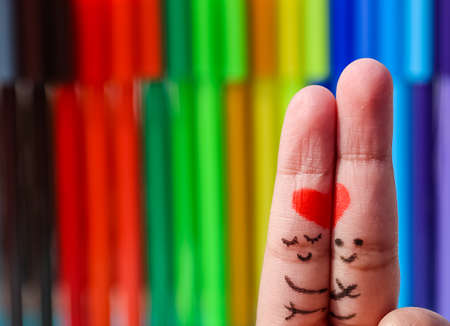 A happy couple in love with painted smiley and hugging art on finger. Valentines day concept with isolated Multi color background with space.の写真素材