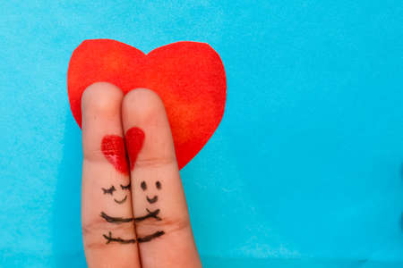 A happy couple in love with painted smiley and hugging art on finger. Valentines day concept with isolated Sky Blue background with space.の写真素材