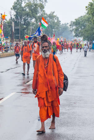 GHAZIABAD, UTTAR PRADESH, INDIA - JULY 2019: A hindu devotee carrying kanwar on their shoulder to perform the yearly kanwar yatra with holy Ganga water walking on streets barefoot.のeditorial素材