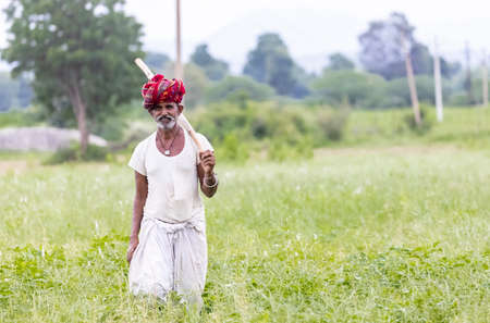 Jawai, Rajasthan, India - September 2021: Portrait of an elderly man of the Rabari ethnic group in a national headdress and traditional white dress and red turban on the field of Jawai.のeditorial素材