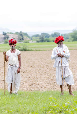 Jawai, Rajasthan, India - September 2021: Portrait of an elderly man of the Rabari ethnic group in a national headdress and traditional white dress and red turban on the field of Jawai.のeditorial素材