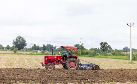 Jawai, Rajasthan, India - September 2021: Indian farmer working on the agriculture fields by the tractor.のeditorial素材