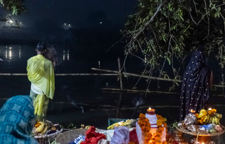 Ghaziabad, Uttar Pradesh, India - November 2021: Chhath Puja, Indian hindu devotees performing rituals of chhath puja during sunrise near river bank.のeditorial素材