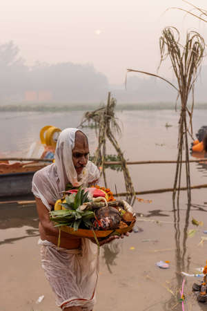 Ghaziabad, Uttar Pradesh, India - November 2021: Chhath Puja, Indian hindu devotees performing rituals of chhath puja during sunrise near river bank.のeditorial素材
