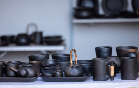 Set of black ceramic pots and cups on the table in the kitchen