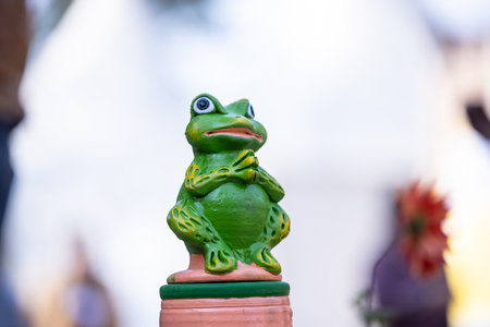Green frog statue on a terracotta pot with a blurred backgroundの写真素材
