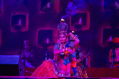 Pushkar, Rajasthan, India - November 2022: An female artist performing rajasthani folk dance Ghoomar in traditional colorful dress and metal pot with fire on head in Pushkar fair.のeditorial素材