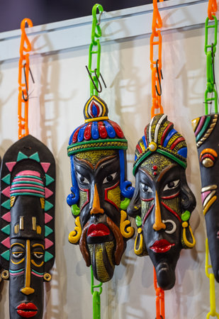 Colorful tribal masks hanging on a wall in a souvenir shopの写真素材
