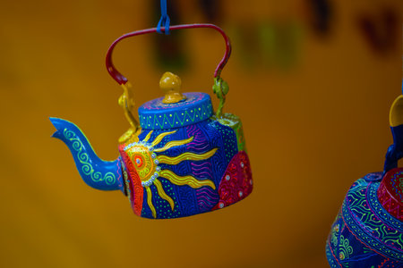 Colorful ceramic teapot on a yellow background.