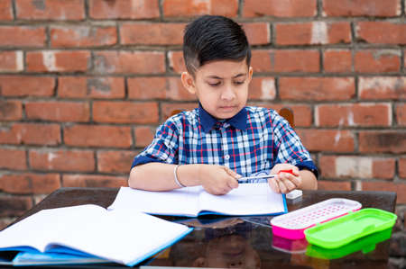 Primary school student in proper school uniform reading book on study table in classroom. Indian education system in Primary school.の写真素材
