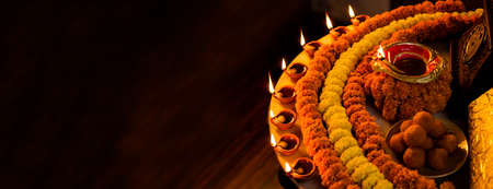 Diwali glowing Diya , flowers, Sweets and Gifts arranged in circular shape forming a design with...