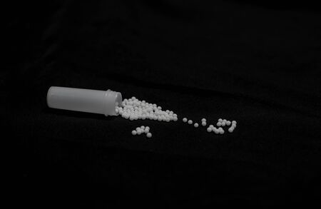 A bottle of homeopathic medicine pills being spilled over a table