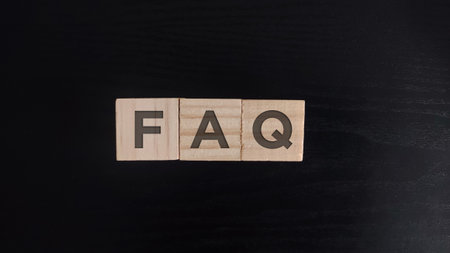 wooden block on black background with the word FAQ frequently asked questionsの写真素材
