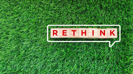 wooden block with RETHINK text and bubble talk icon on grass background. Rethink and reevaluate in business conceptの写真素材