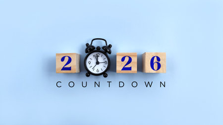 countdown 2026 text on wood block with black alarm clock on blue background. Countdown Happy new year concept.の写真素材