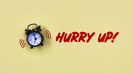Conceptual black alarm clock with text HURRY UP on yellow backgroundの写真素材