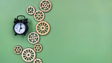 Conceptual black alarm clock with gears on green background. Time progress conceptの写真素材
