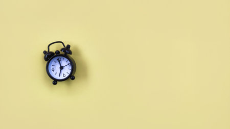 Conceptual black alarm clock on yellow backgroundの写真素材