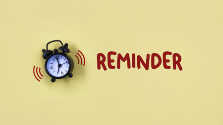 Alarm clock with REMINDER word on yellow background. Time management concept