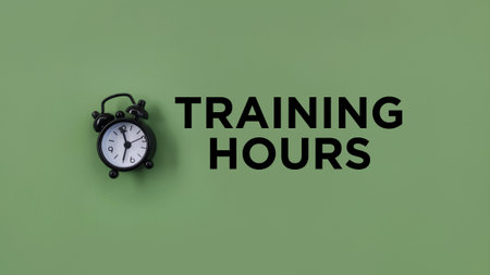 Conceptual black alarm clock with text TRAINING HOURS on green backgroundの写真素材