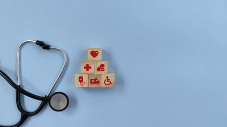 Stethoscope on isolated blue background with wood block with healthcare medical icon. Health insurance concept.の写真素材