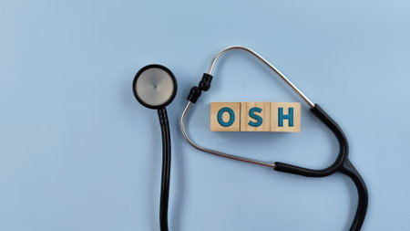 Stethoscope on isolated blue background with wooden cube, text OSH. Occupational Safety and Health conceptの写真素材